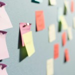 Sticky notes in various colours on a cardboard displayed with a narrow depth of field.