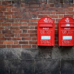 Two Danish Post Danmark mail boxes mounted on a brick wall.