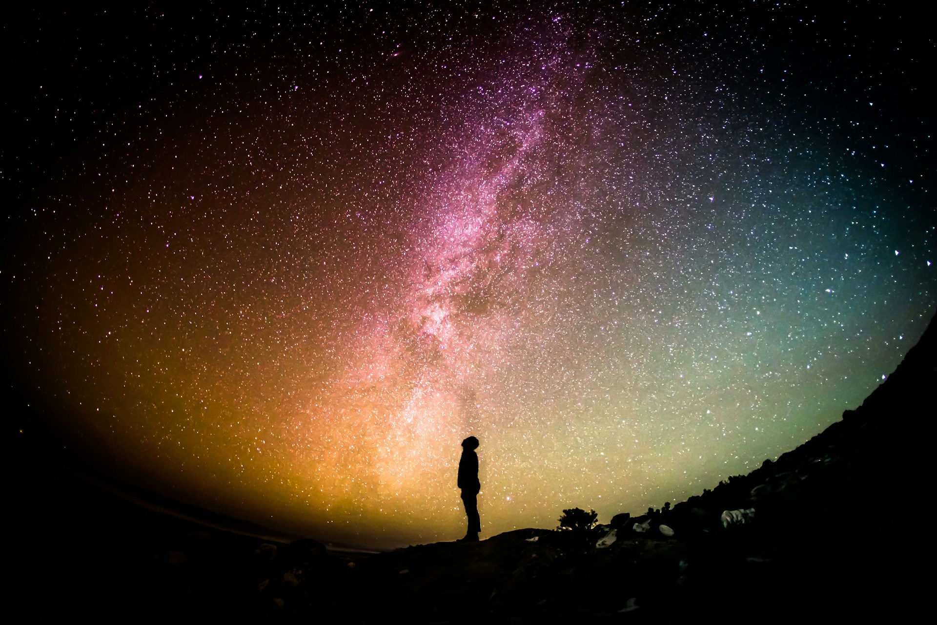 Man looking up at the night lit sky and the milky way.