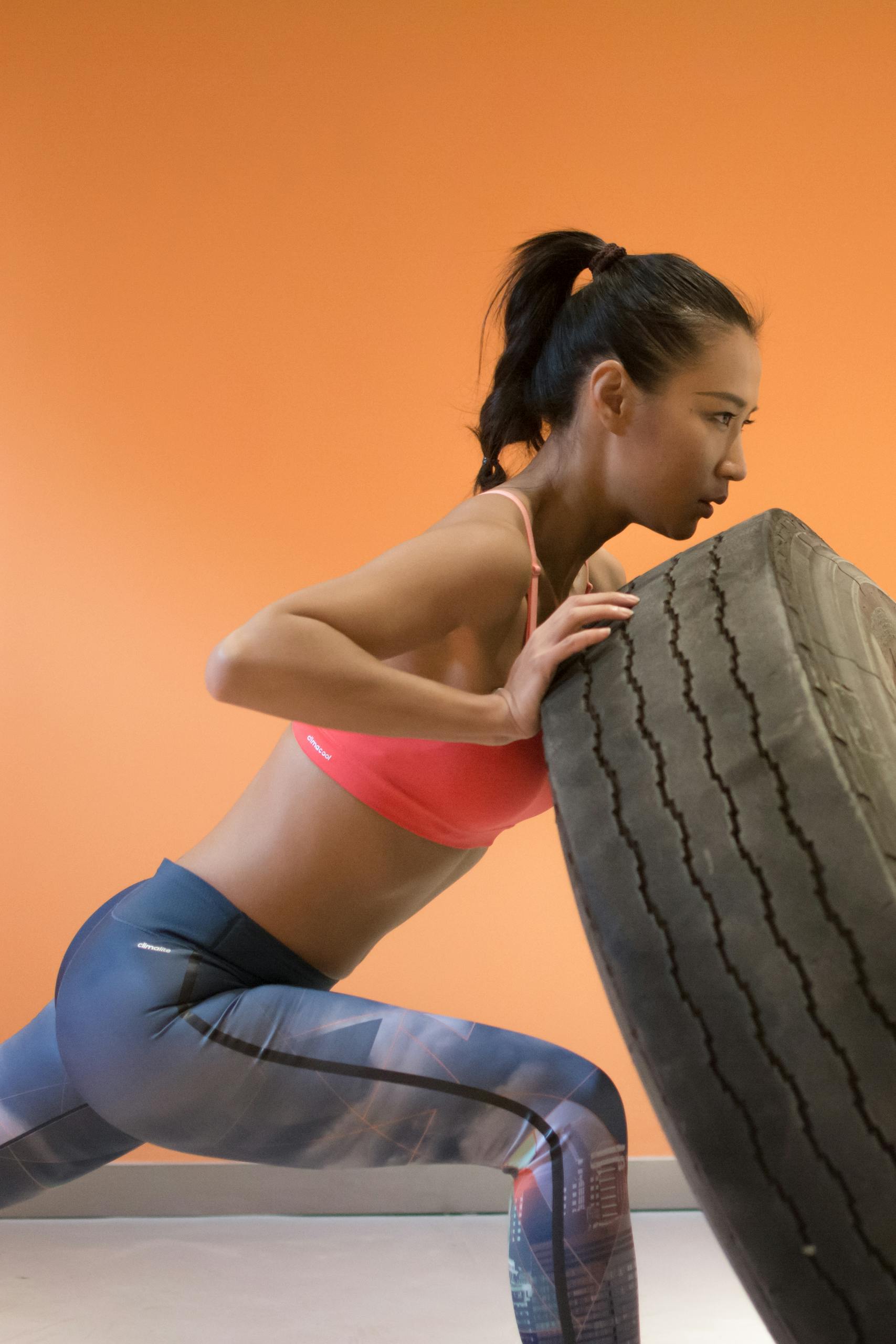 Strong woman pushing tire during gym workout, showcasing fitness and determination.