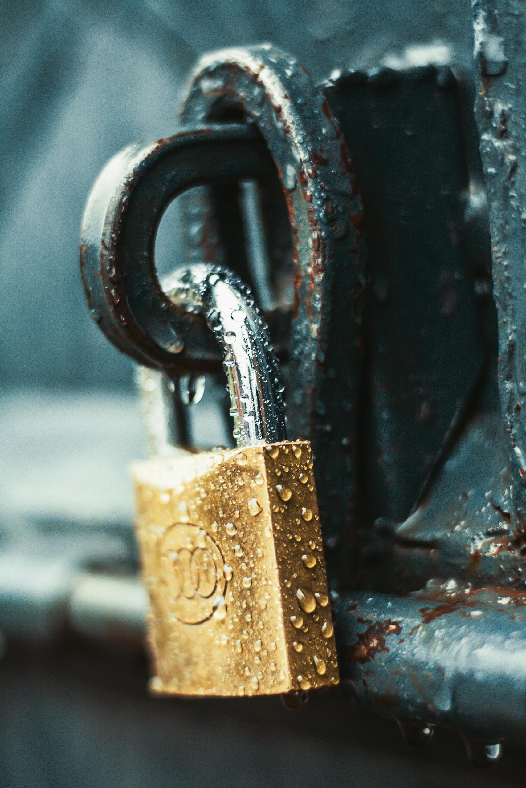 A detailed shot of a wet padlock on a rusty metal surface, showcasing textures and water droplets.