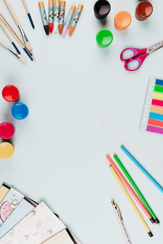 Flat lay of colorful art supplies on a light background with ample copy space.